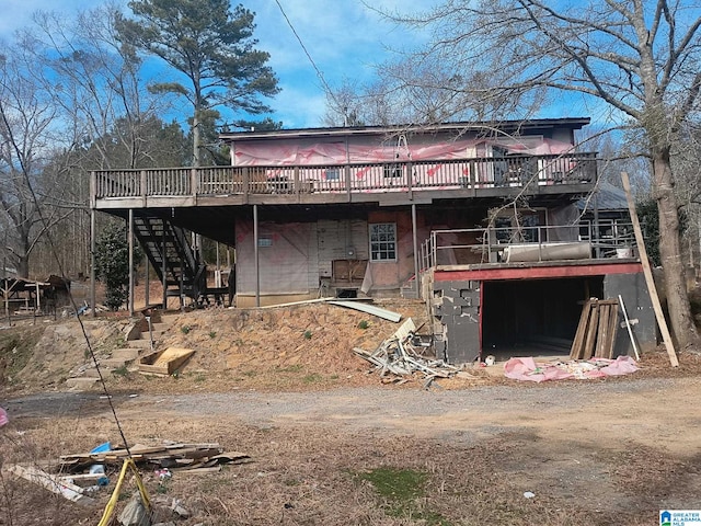 back of property with dirt driveway, stairway, and a wooden deck