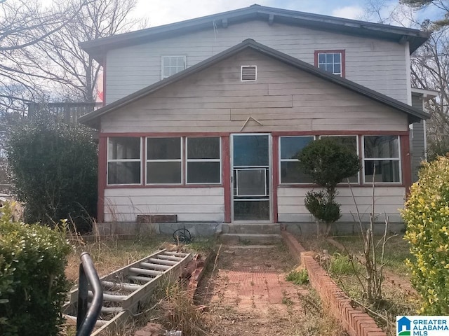 back of property featuring entry steps and a garden