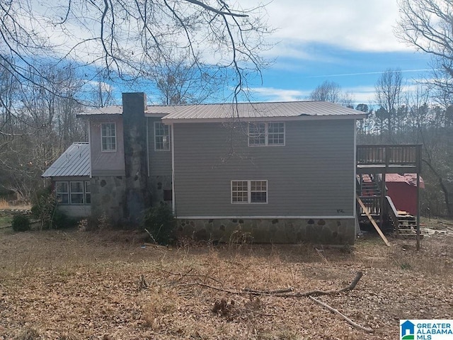 back of property with a deck, stairs, a chimney, and metal roof