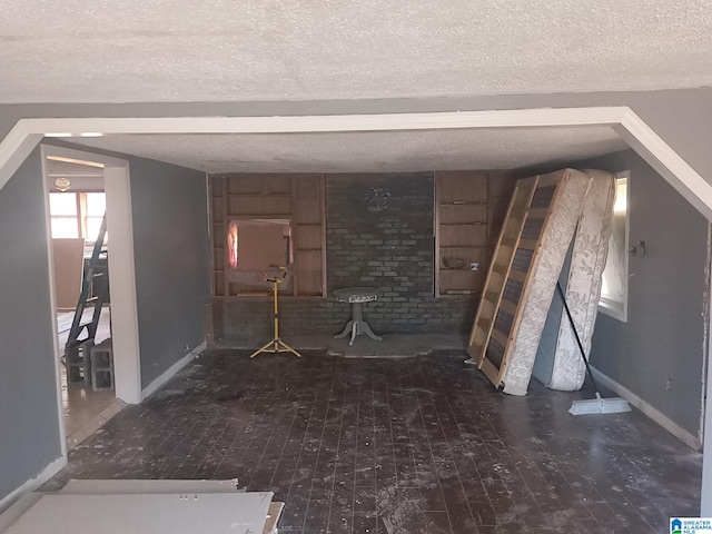 interior space featuring baseboards, a textured ceiling, and wood finished floors