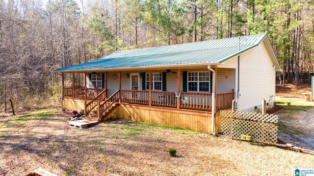 view of front of house with metal roof, ceiling fan, a porch, and a view of trees