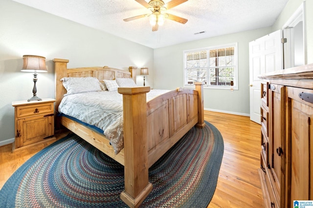 bedroom with visible vents, baseboards, ceiling fan, a textured ceiling, and light wood-style floors