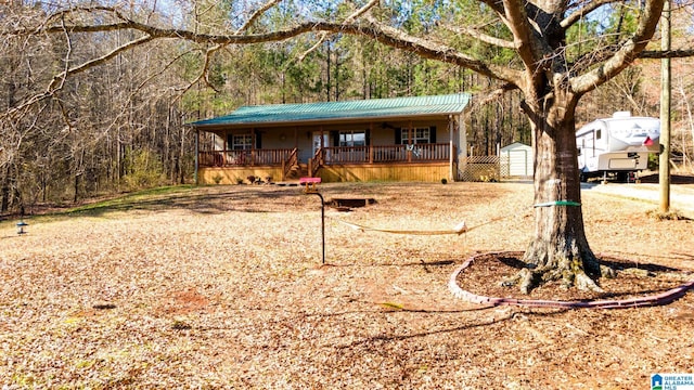 view of front of home featuring covered porch, a shed, metal roof, and an outbuilding