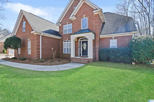 traditional home with a front yard, brick siding, and roof with shingles