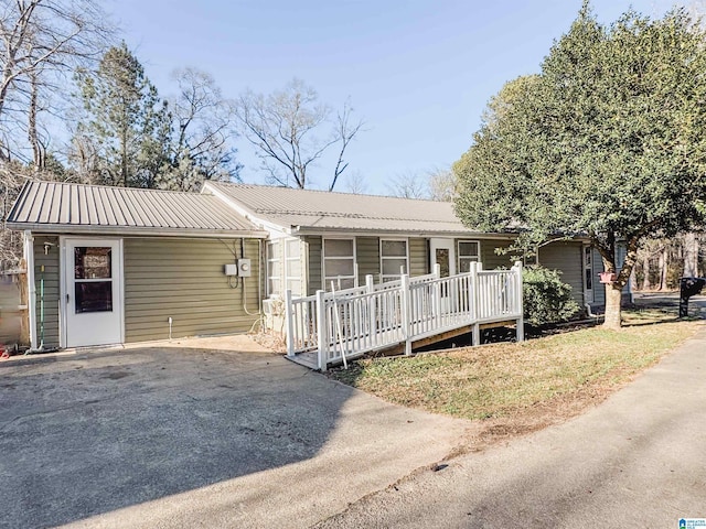 ranch-style home with metal roof, a porch, and driveway