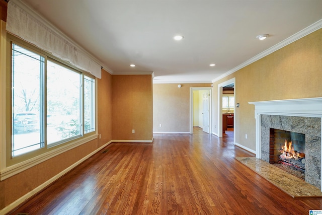 unfurnished living room featuring ornamental molding, a premium fireplace, wood finished floors, and baseboards