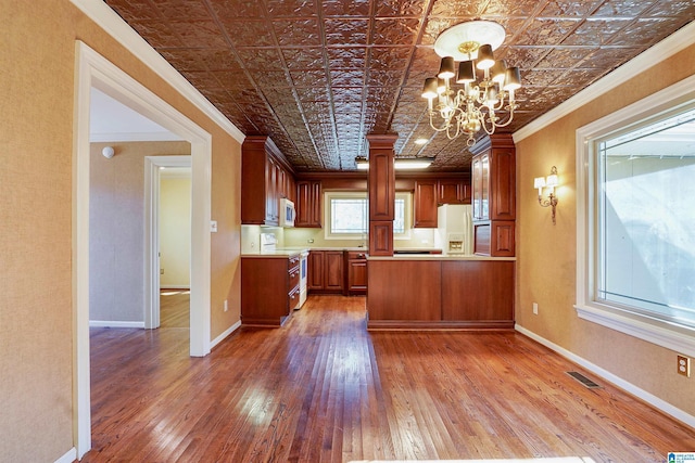 kitchen featuring an ornate ceiling, a notable chandelier, ornamental molding, white appliances, and baseboards