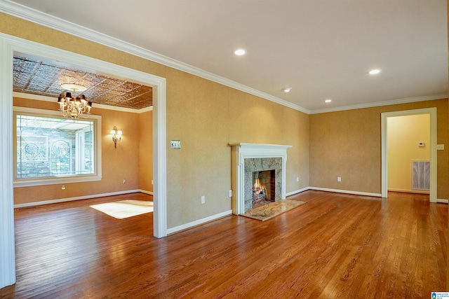 unfurnished living room with crown molding, visible vents, a premium fireplace, wood finished floors, and baseboards