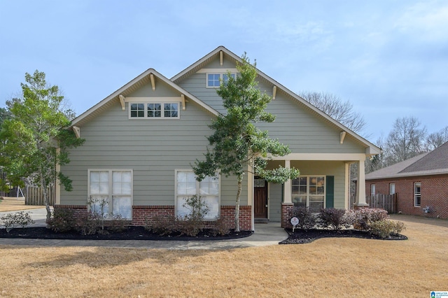 craftsman house featuring covered porch, a front lawn, and brick siding