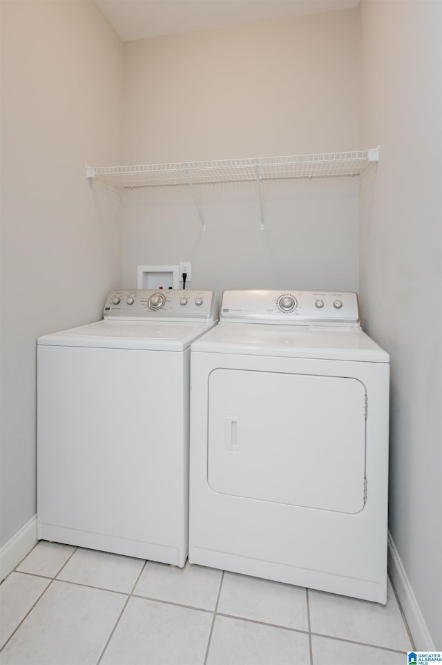 laundry area featuring laundry area, light tile patterned flooring, washing machine and clothes dryer, and baseboards