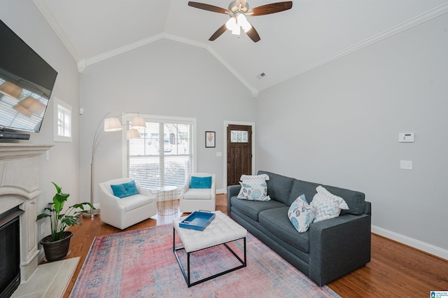 living area with a healthy amount of sunlight, a fireplace with raised hearth, crown molding, and wood finished floors