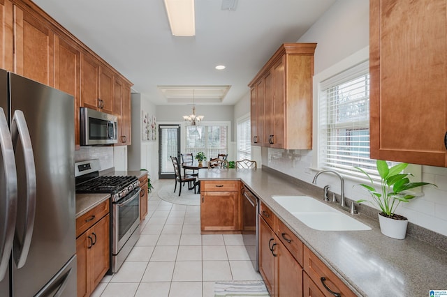 kitchen featuring light tile patterned floors, a sink, a healthy amount of sunlight, appliances with stainless steel finishes, and brown cabinetry