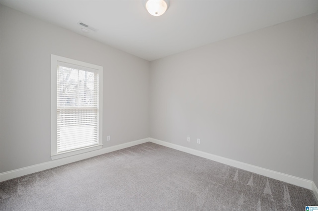 carpeted spare room featuring baseboards and visible vents