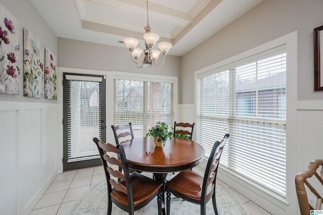 dining room featuring a chandelier, a wainscoted wall, crown molding, and light tile patterned floors