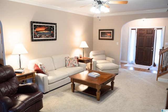 living room with arched walkways, stairway, ornamental molding, ceiling fan, and baseboards