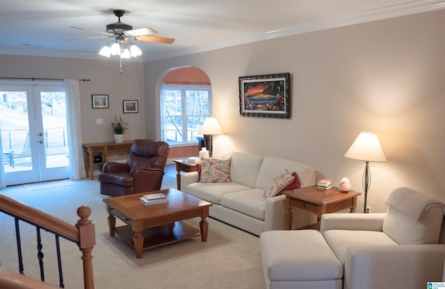 living room with a ceiling fan, french doors, crown molding, and light colored carpet