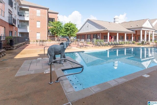 view of swimming pool featuring a patio area and fence