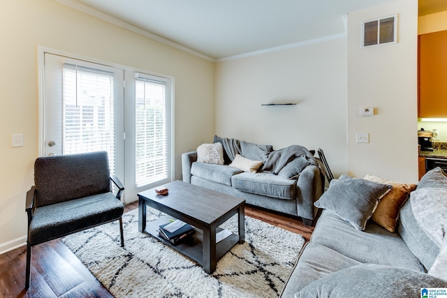 living area featuring visible vents, crown molding, baseboards, and wood finished floors