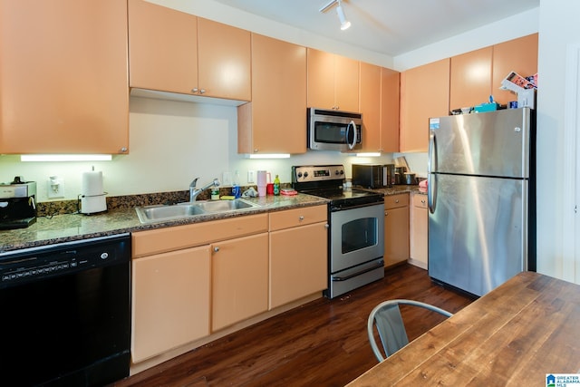 kitchen with a sink, appliances with stainless steel finishes, dark countertops, dark wood finished floors, and rail lighting