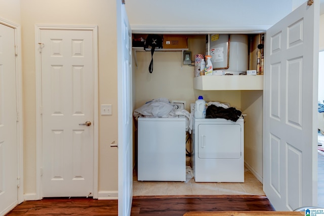 laundry area with washing machine and dryer, laundry area, baseboards, water heater, and tile patterned floors