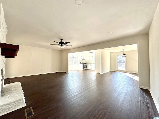 unfurnished living room featuring dark wood-style floors, ceiling fan, a fireplace, and visible vents