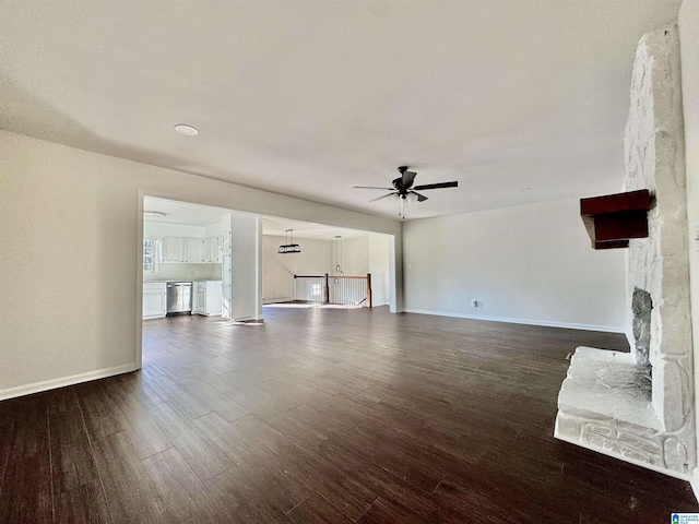 unfurnished living room featuring dark wood-style flooring, a fireplace, baseboards, and ceiling fan