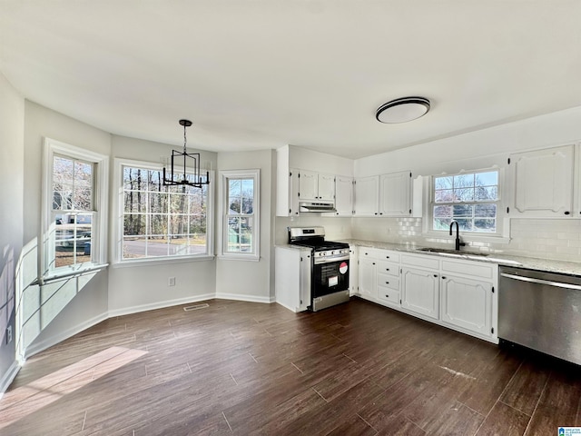 kitchen featuring tasteful backsplash, white cabinets, dark wood finished floors, stainless steel appliances, and a sink