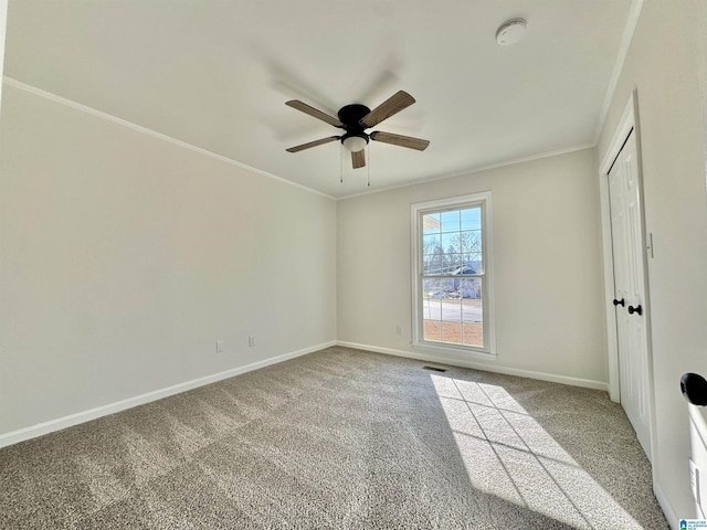 interior space with baseboards, visible vents, a ceiling fan, ornamental molding, and carpet floors