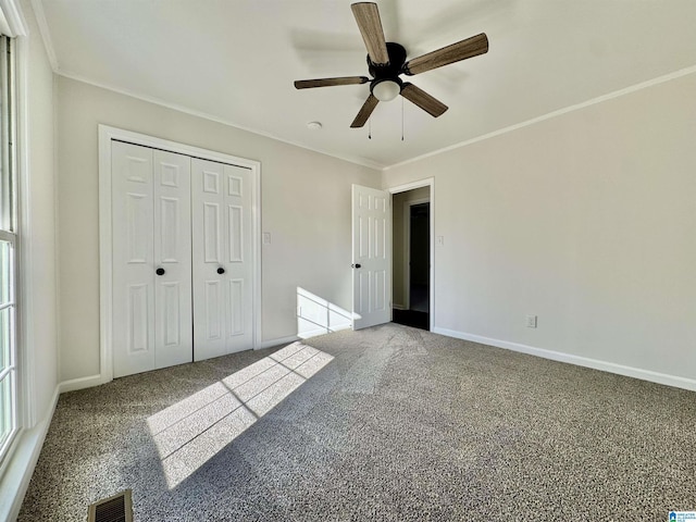 unfurnished bedroom with baseboards, visible vents, crown molding, carpet floors, and a closet