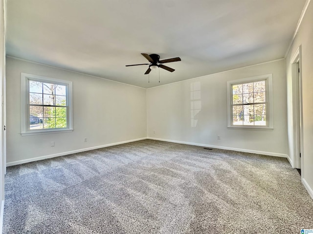 spare room with dark colored carpet, a healthy amount of sunlight, ceiling fan, and baseboards