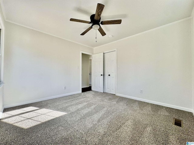 carpeted empty room featuring ornamental molding, a ceiling fan, visible vents, and baseboards