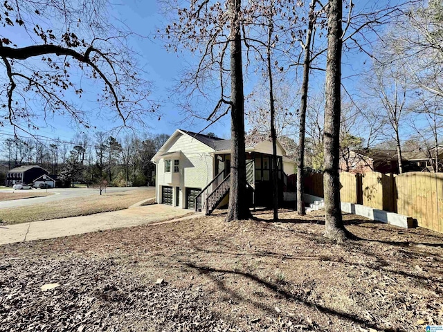 view of side of property with driveway, stairway, a garage, and fence