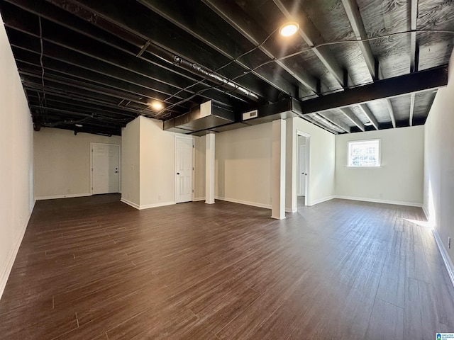 below grade area featuring visible vents, dark wood finished floors, and baseboards