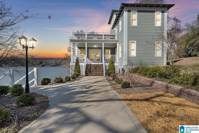 view of front of house featuring french doors, a porch, stairway, and a balcony