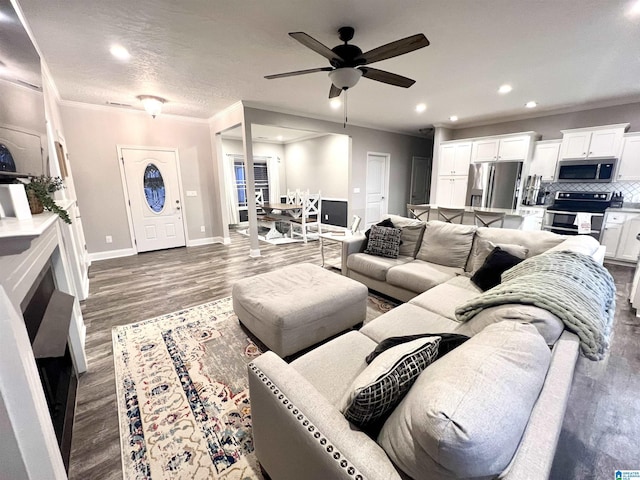 living area with crown molding, recessed lighting, ceiling fan, wood finished floors, and baseboards