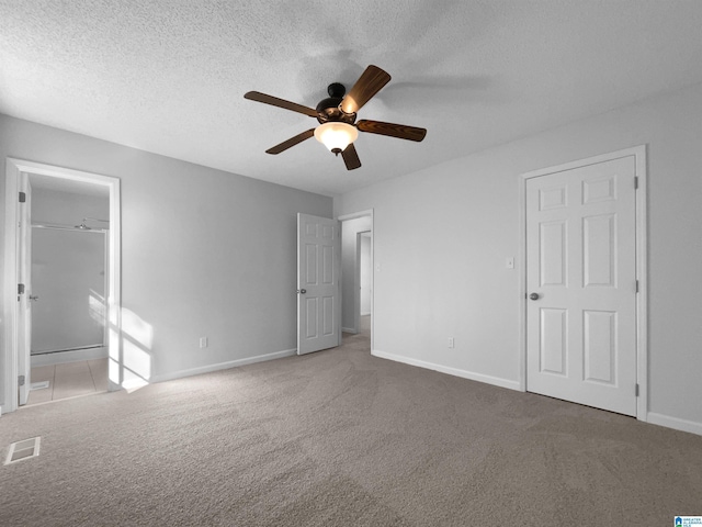 unfurnished bedroom with carpet floors, visible vents, a textured ceiling, and baseboards