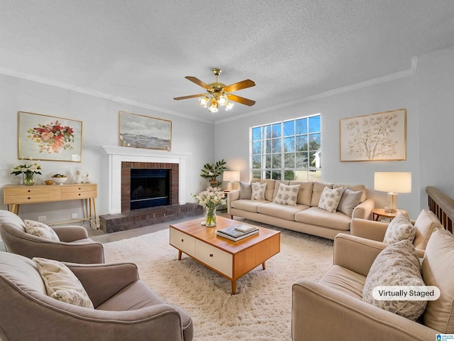 living area with ornamental molding, a brick fireplace, ceiling fan, and a textured ceiling