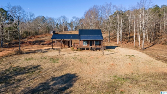 rustic home with dirt driveway, metal roof, and a deck