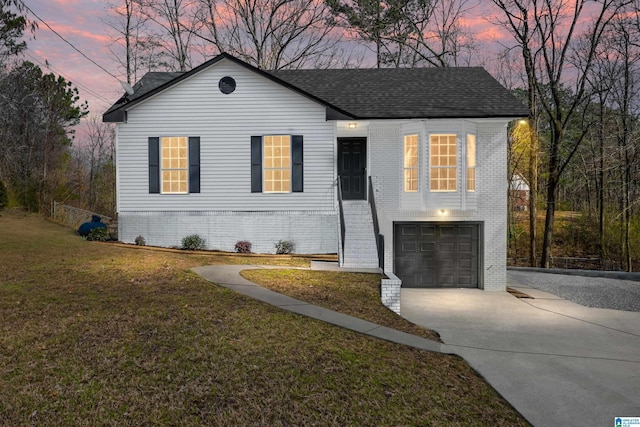 view of front of property with a garage, a shingled roof, a lawn, concrete driveway, and brick siding