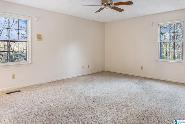 carpeted empty room featuring baseboards, ceiling fan, visible vents, and a textured ceiling