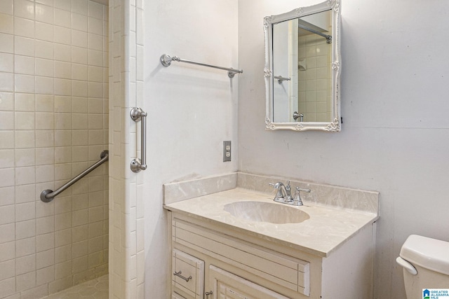 bathroom featuring a tile shower, vanity, and toilet