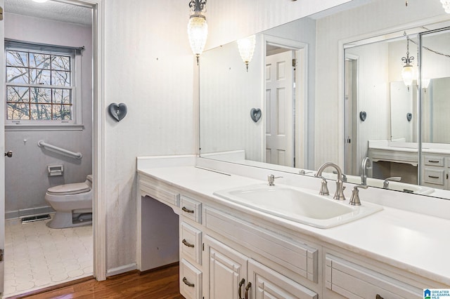 bathroom featuring a textured ceiling, toilet, wood finished floors, visible vents, and vanity