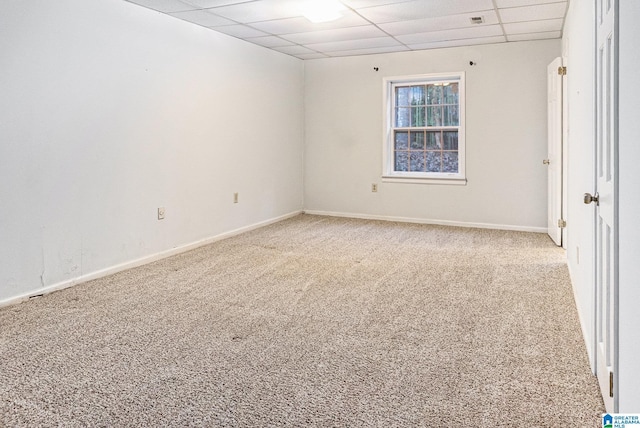 empty room with carpet floors, a drop ceiling, and baseboards