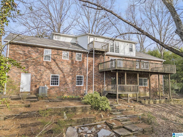 rear view of house with brick siding, a balcony, and central air condition unit