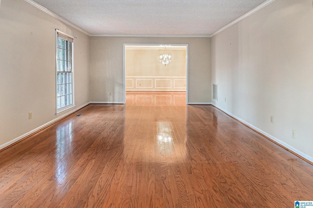 unfurnished living room featuring crown molding, a notable chandelier, visible vents, a textured ceiling, and wood finished floors