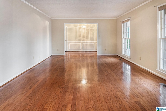 empty room featuring baseboards, ornamental molding, and wood finished floors