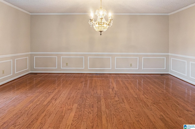 empty room featuring a chandelier, light wood-type flooring, and a decorative wall