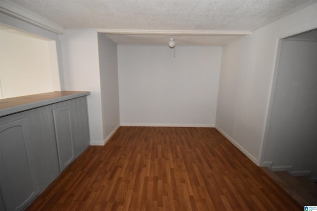 empty room with a textured ceiling, wood finished floors, and baseboards