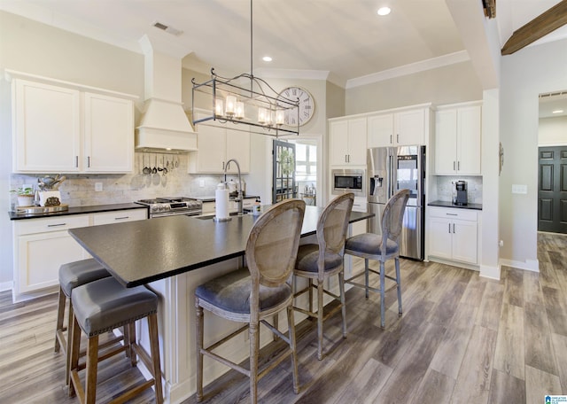 kitchen featuring premium range hood, visible vents, appliances with stainless steel finishes, decorative backsplash, and dark countertops