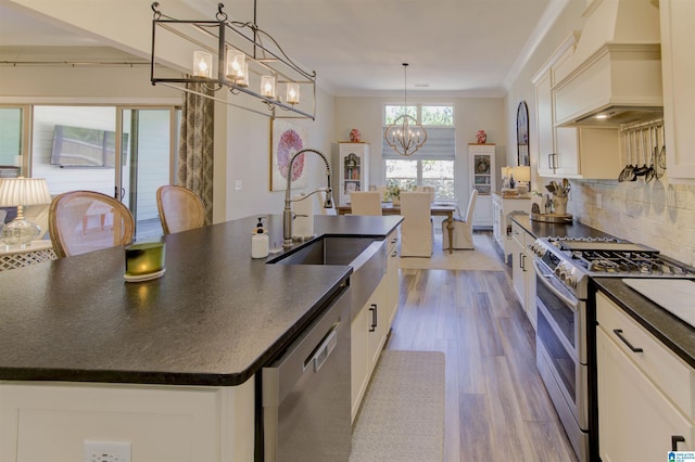 kitchen featuring a chandelier, appliances with stainless steel finishes, ornamental molding, dark countertops, and custom range hood